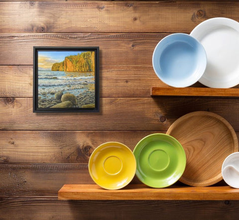 Colorful bowls and a wooden tray on a wooden shelf with a framed picture Mazinaw Magic by Karen Richardson, in the background.