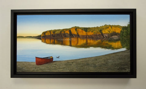 Framed painting of a red canoe on a beach with a scenic landscape of cliffs and water. Titled Mazinaw Mirror by  Karen Richardson