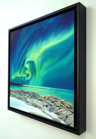 Rhythms of the Night by Karen Richardson.
Framed painting of northern lights over a rocky shoreline with water below.