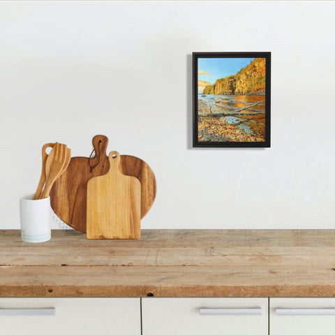 Framed landscape painting of a lake, cliffs, and trees with autumn colours, titled Mazinaw Majesty by Karen Richardson, shown in a kitchen setting.