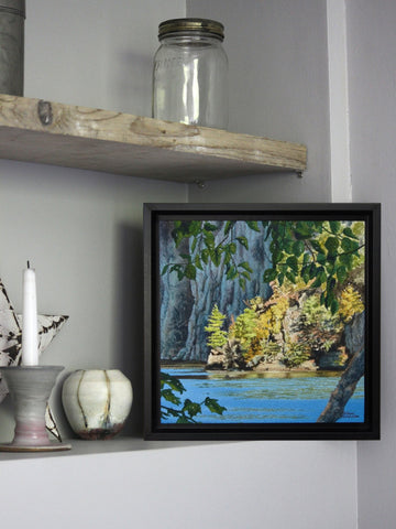Painting of trees, rocks and lake displayed on a rustic shelf. Paint titled Mazinaw Moment by Karen Richardson