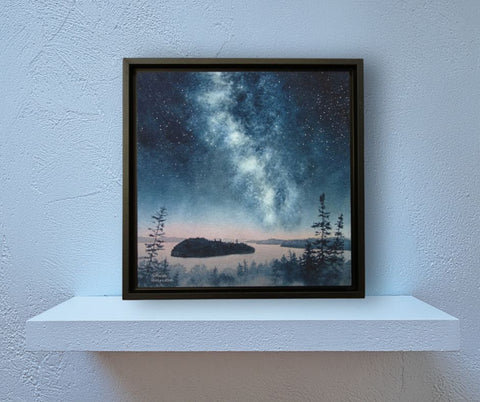A painting of Lake Superior islands under a starry night sky with the Milky Way, titled Starlit Shores, by Karen Richardson, shown on an interior shelf.